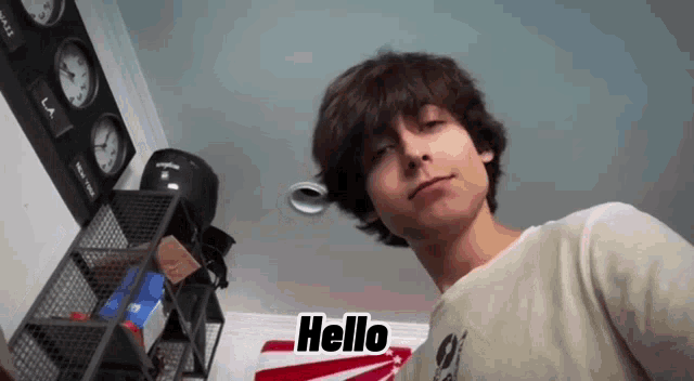 a young man is standing in a room with a sign that says hello