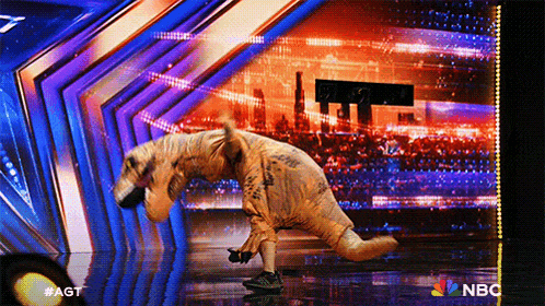 a person dressed as a dinosaur on a stage with a nbc logo