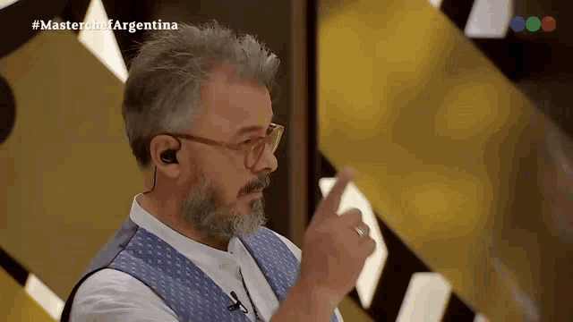 a man with a beard and ear buds is on a television show called master chef argentina