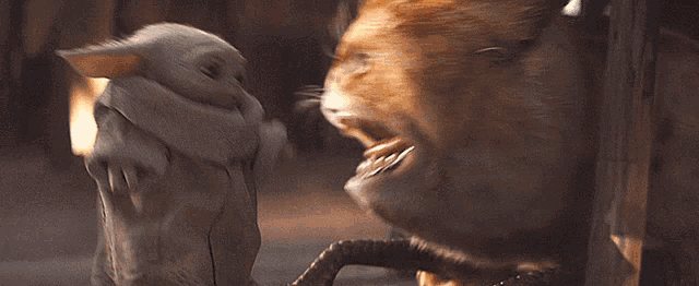 a stuffed animal is standing next to a cat with a big mouth