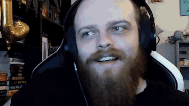 a man with a beard is wearing headphones and smiling .