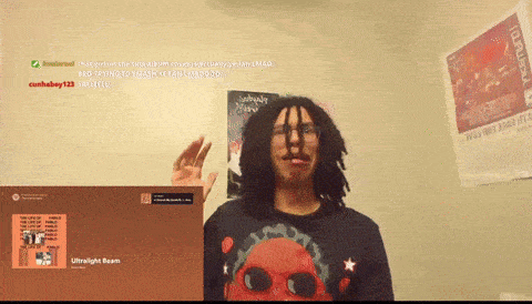 a man with dreadlocks stands in front of a poster that says ultralight beam on it