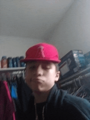 a young boy wearing a red hat and a black jacket is taking a selfie in a closet .