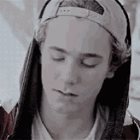 a young man wearing a baseball cap with a hood is looking down .
