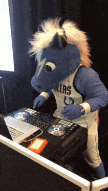 a mascot wearing a dallas jersey playing music