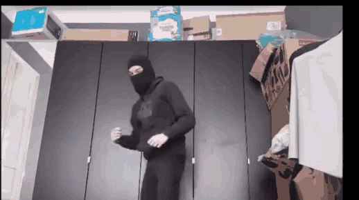 a man wearing a ski mask is standing in front of a closet .