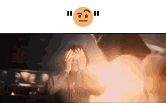 a man is covering his face with his hands in front of a fire while a smiley face is above him .