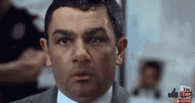 a man in a suit and tie is making a funny face while looking at the camera .