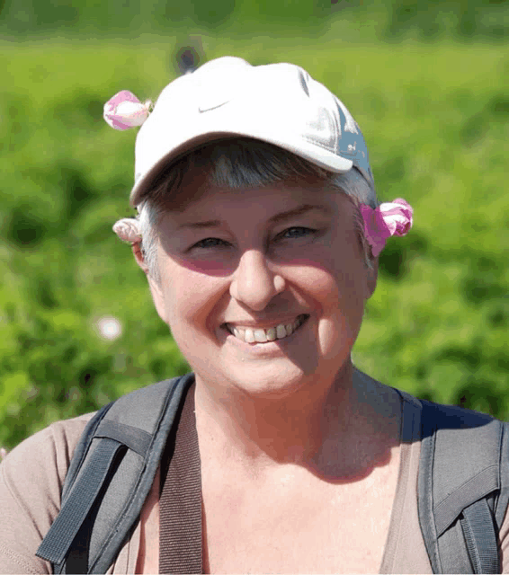 a woman wearing a white nike hat with pink flowers on her ear