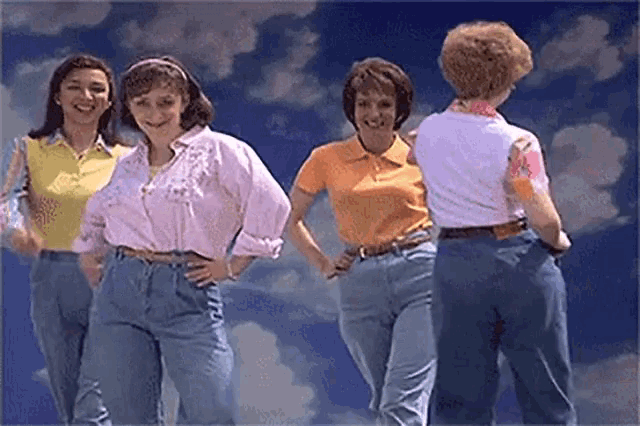 a group of women are standing next to each other with their hands on their hips .