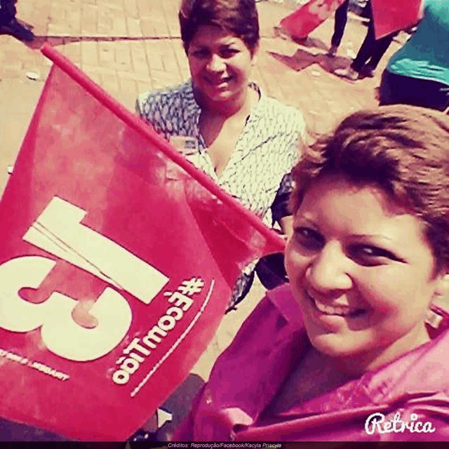 two women holding a red flag that says 13 on it