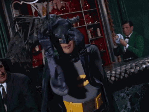 a man in a batman costume is covering his eyes with his hands