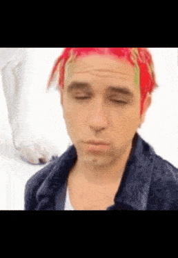 a man with red hair and green dreadlocks is making a funny face