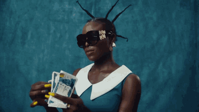 a woman wearing sunglasses holds a bunch of money in her hand