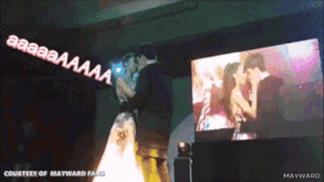 a bride and groom are kissing in front of a screen that says courtesy of mayward fans on it