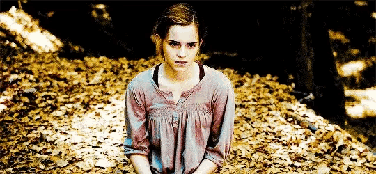 a woman is sitting on a pile of leaves in the woods