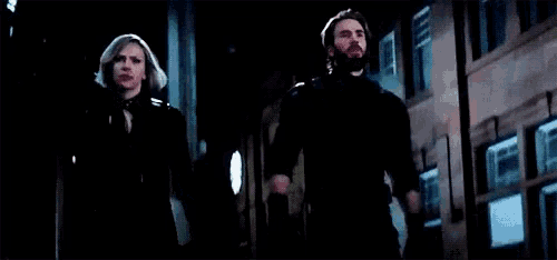 a man and a woman are standing next to each other on a city street at night .