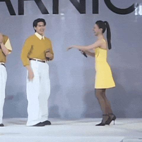 a woman in a yellow dress stands in front of a man in a yellow shirt