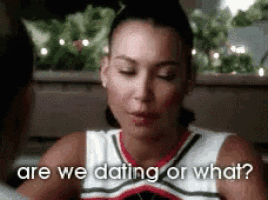 a woman in a cheerleading uniform is sitting in a car talking to another woman .