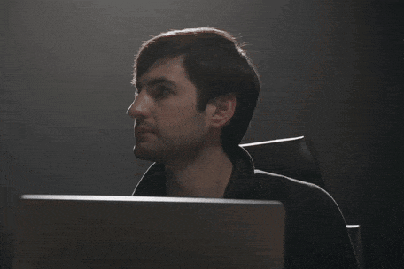 a man in a suit is looking at a laptop