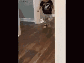 a young boy is running down a hallway .