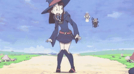 a girl in a witch costume is standing in front of a group of zombies .