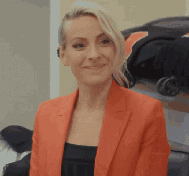 a woman wearing a red blazer is smiling and looking at the camera