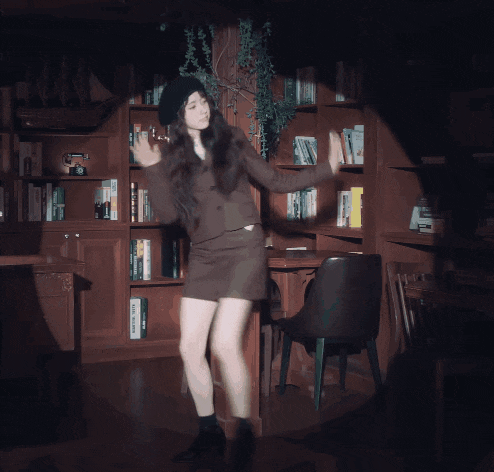 a woman is dancing in front of a bookshelf that has a book called " a brief history " on it