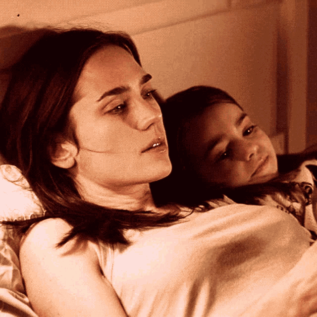 a woman and a child are laying on a bed