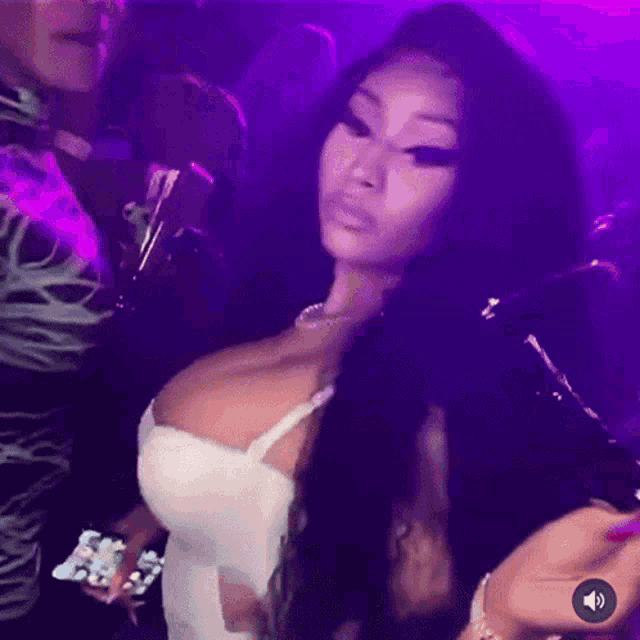 a woman in a white dress is dancing in a club with purple lights behind her