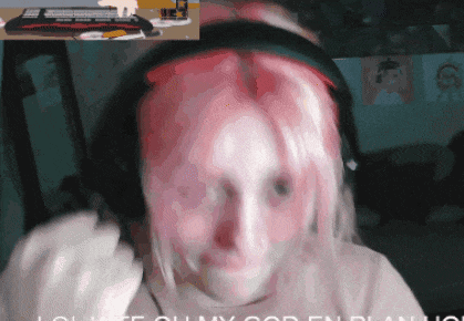 a woman with pink hair is wearing headphones and a keyboard is behind her