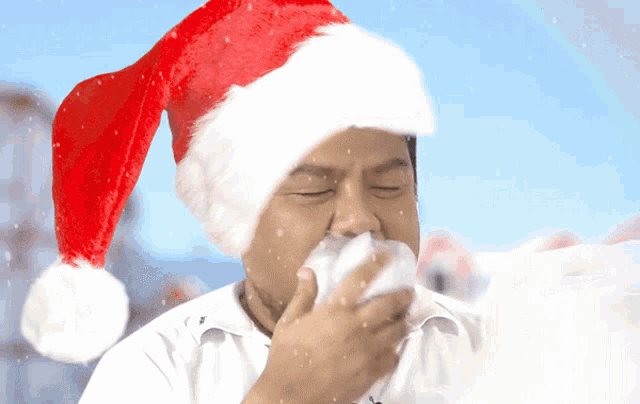 a man in a santa hat blows his nose