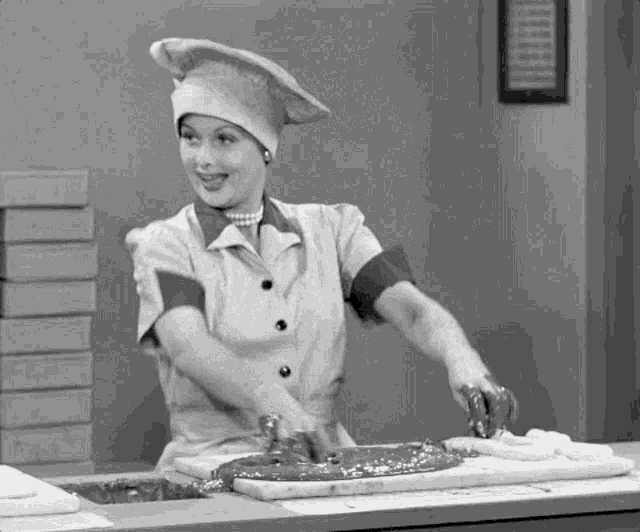 a black and white photo of a woman wearing a chef hat