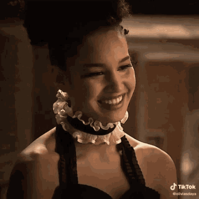a young woman wearing a choker and earrings is smiling .