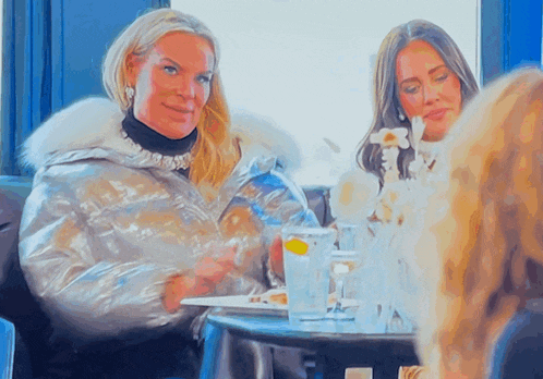 two women are sitting at a table with glasses of water and plates of food