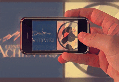 a person is holding a cell phone with a picture of a mountain and the words " conquerations of achievers " on the screen