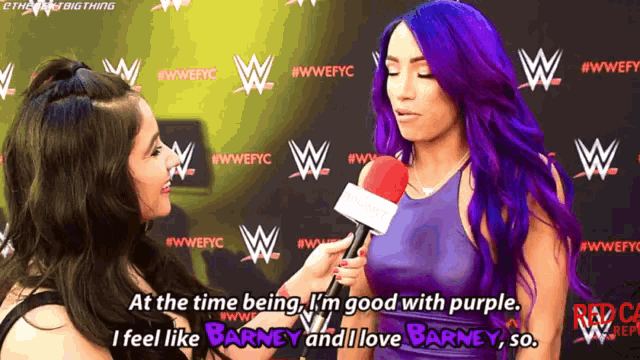 a woman with purple hair is talking to another woman with a microphone