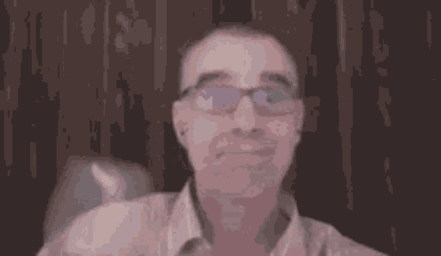 a man wearing glasses is holding a balloon in his hand and smiling .