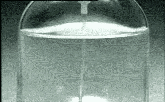 a glass container filled with water is being poured into another glass container .