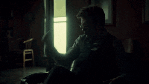 a man in a wheelchair is holding a cane in a dark room