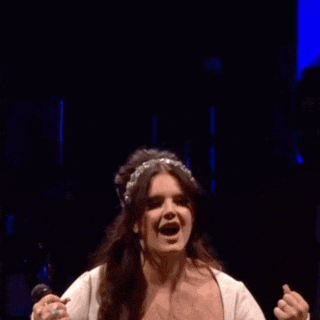 a woman in a white dress is holding a microphone and singing