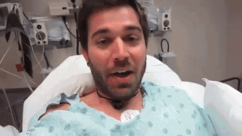 a man in a hospital gown with a necklace around his neck