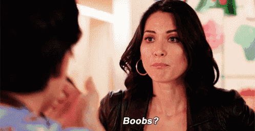 a woman in a leather jacket is talking to a man and asking him about her breasts .