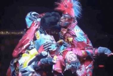 a group of people in colorful costumes are standing next to each other on a stage in a dark room .