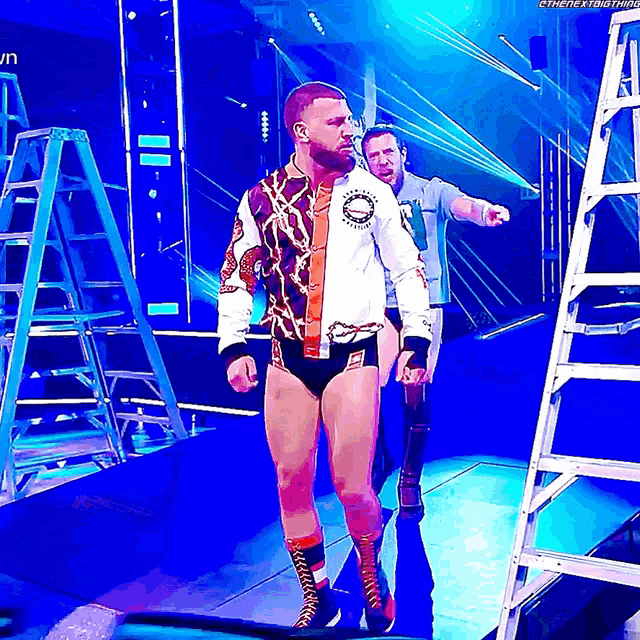 a wrestler is walking down the aisle with a ladder behind him