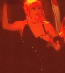 a woman in a black dress is dancing with her arms in the air .
