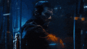 a man is standing in a dark room behind a glass wall .