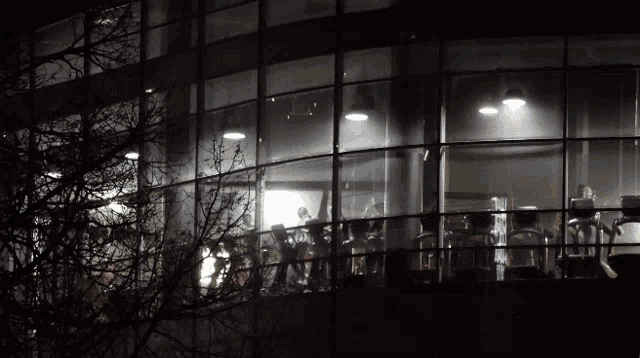a gym is lit up at night with people using treadmills and bikes