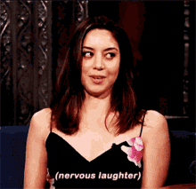a woman in a black dress is smiling and saying nervous laughter