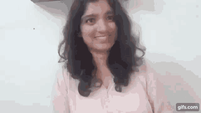 a woman in a pink shirt is smiling at the camera .